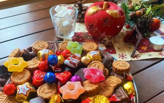 Nikolausteller mit Suüßigkeiten und Keksen, im Hintergrund weihnachtliche Deko